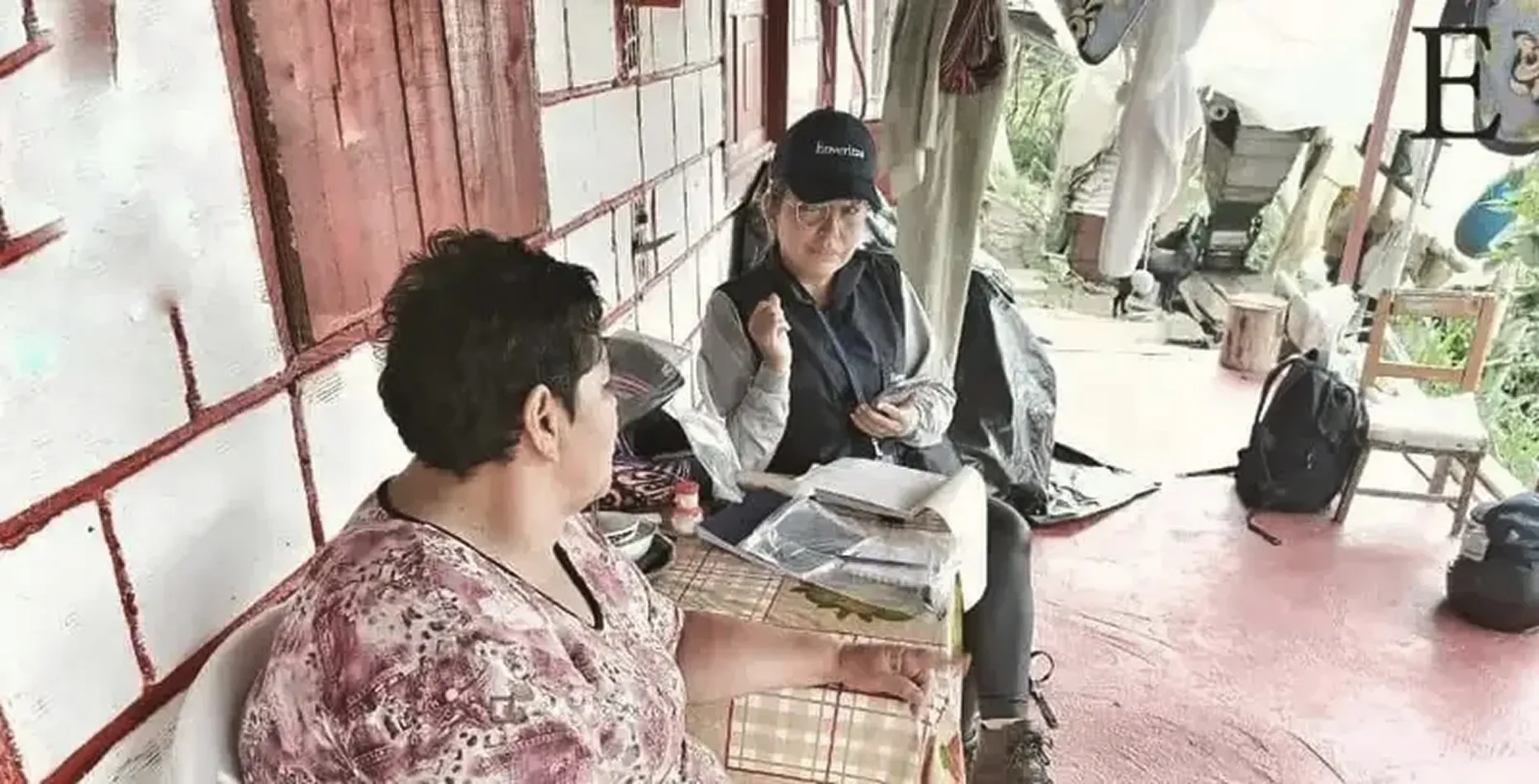 An Enumerator interviews a coffee farming household member while seated on a rural porch in Honduras.